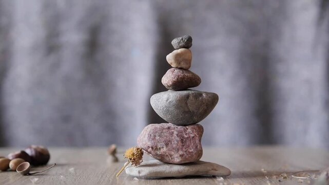 6x Slow Motion Macro of White Seeds Blowing Off a Stacked Stone Cairn Against a Gray Background b-roll