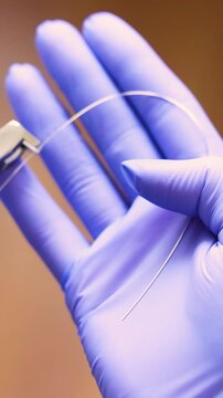 Dentist hands handling orthodontic ligature wire with needleholder instrument for braces adjustment