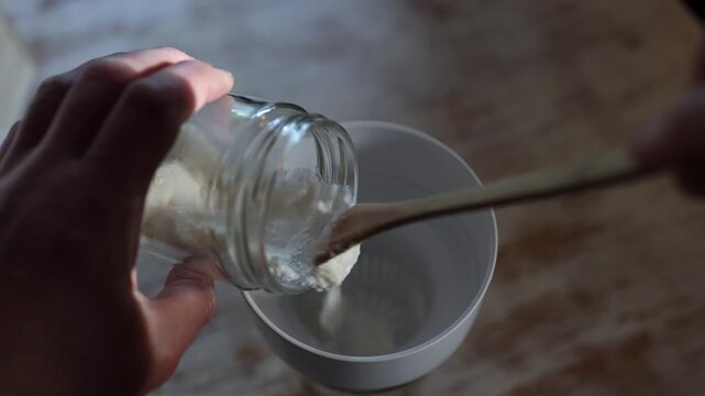 Homemade milk kefir fermentation using kefir grains in a glass jar. Natural probiotic drink preparation with live cultures and healthy fermented dairy.