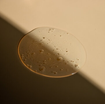 Smudge of bubbled transparent gel or cosmetic serum bisected by sharp diagonal sunlight. Reflects refreshing aquatic energy and deep cleansing. Ideal for summer sunscreen promos.