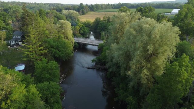 Flying south over the Creditview Road bridge over the Credit River to farmland in the Cheltenham area, a community within the town of Caledon, Ontario, Canada. Shot by a drone on a summer afternoon.