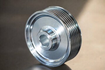 Obraz premium A shiny, polished aluminum belt tensioner rests on a metallic surface.