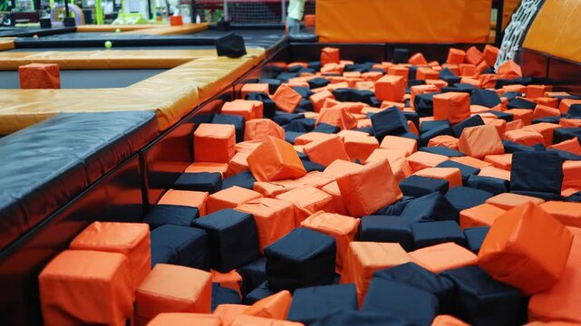 Kids playing on indoor playground in foam rubber pit in trampoline, active pastime in the amusement park. 
