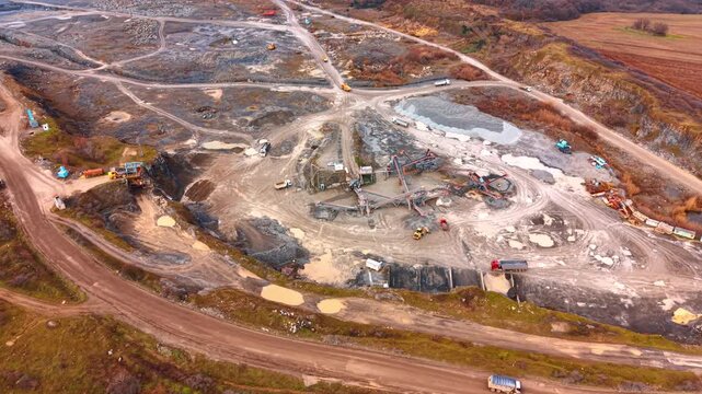 Aerial view of stone crushing plant and industrial quarry. Wide high angle view of mining equipment, conveyor belts, and trucks in a gravel quarry.