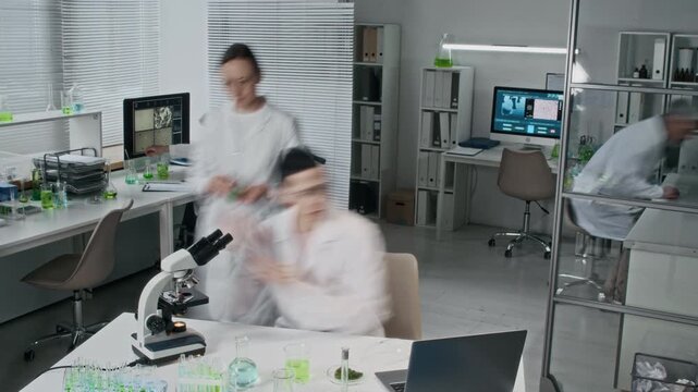 Team of scientists moving fast working in modern laboratory setting doing various tasks with one person using wheelchair, time lapse shot, copy space