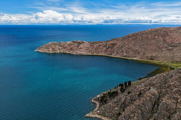 Fototapeta premium Aerial view of lake bay next to rocky mountains sunny
