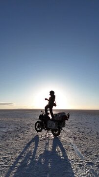 Man riding adventure motorcycle on Salar de Uyuni. Endless white landscape and rider on the vast Bolivian salt flats.