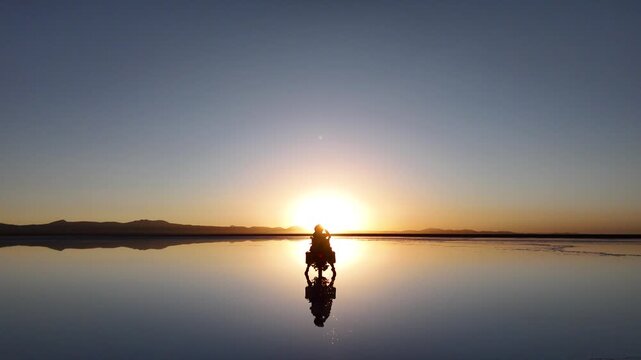 Man riding adventure motorcycle on Salar de Uyuni. Endless white landscape and rider on the vast Bolivian salt flats.