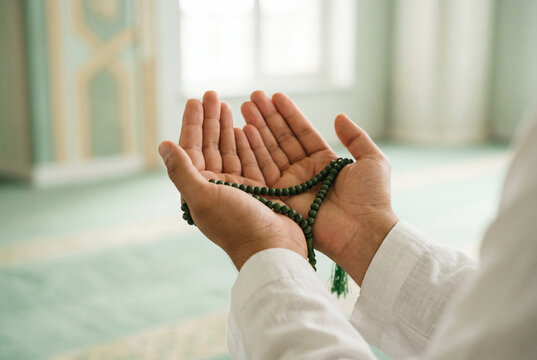 Muslim man holding prayer beads in open hands during devotion