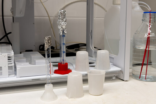 Laboratory equipment. Plastic beakers, glass measuring cylinders and autosampler