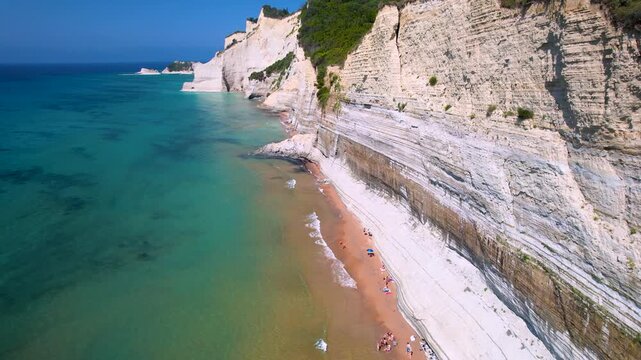 Loggas Beach 4k drone pull back from white vertical cliffs and narrow beach in Corfu. Aerial view of Sidari Peroulades coastline and turquoise sea in Greece. Scenic mediterranean travel scenery