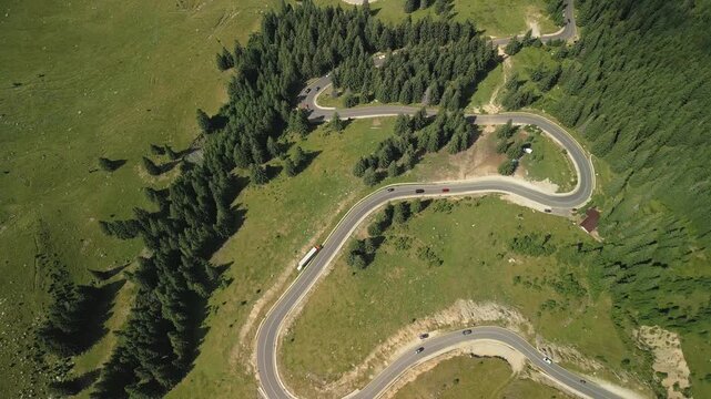 Aerial top down view of Transfagarasan winding mountain road with traffic, slow forward flight over scenic switchbacks in Romania