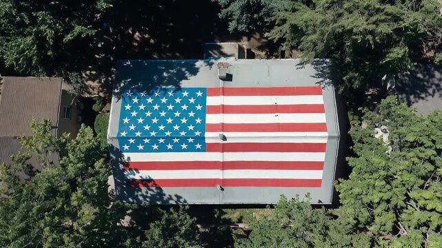 An aerial top-down view of a house roof painted with a large American flag Seamless Loop