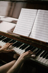 Beautiful young woman playing vintage piano in a cozy room.