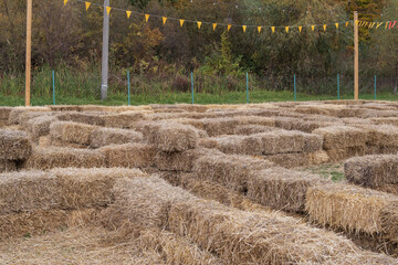 Hay bales stacked to create a maze structure at a countryside farm festival. Traditional rustic attraction during harvest season. © Olha