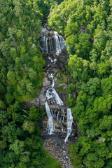 Obraz premium Amazing summer landscape with forest river waters falling down in big waterfall with clear water between rocky boulders in Nantahala National Forest. Whitewater Falls, North Carolina, USA