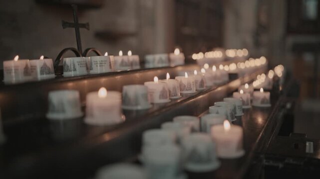Rows of burning votive candles inside a historic church in Erfurt, Germany. Warm candlelight creates a peaceful spiritual atmosphere of prayer, remembrance, and religious tradition.