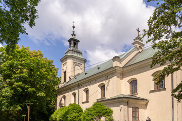 Historic church stands among trees under a bright sky in summer