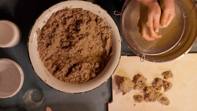 Step 3 of papier mache process. Hands squeezing soaked recycled paper pulp to remove water and prepare material for handmade craft mixture