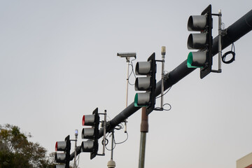 Suspended roadway traffic lights with illuminated signals, monitoring devices, and black mast arm structure