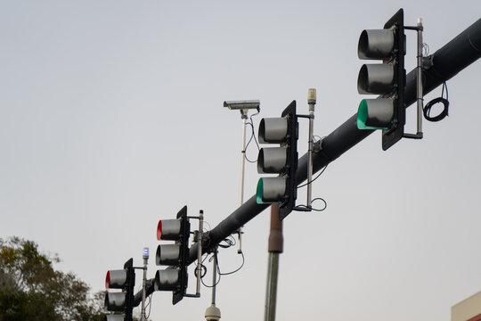 Suspended roadway traffic lights with illuminated signals, monitoring devices, and black mast arm structure