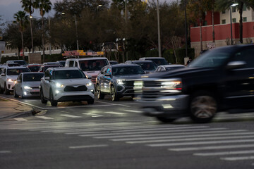 Urban roadway congestion in Orlando, Florida showing a busy crosswalk, multiple traffic lanes, headlights, and mixed vehicles at twilight hour