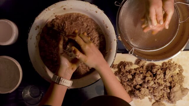 Step 3 of papier mache process. Hands squeezing soaked recycled paper pulp to remove water and prepare material for handmade craft mixture