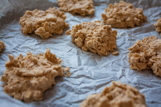 Baking tray with uncooked raw oatmeal cookie dough on a white baking paper