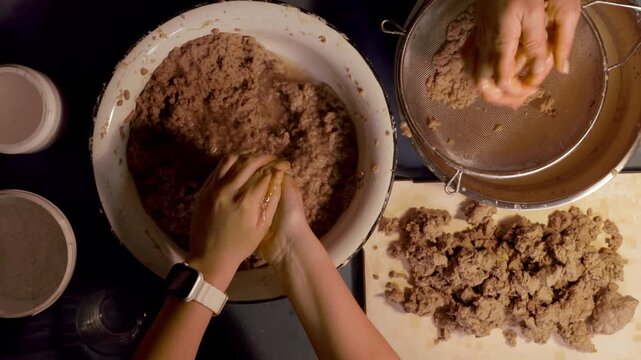 Step 2 of papier mache making process. Hands soaking torn egg carton pieces in water to soften recycled paper for craft pulp mixture. DIY recycled paper craft preparation