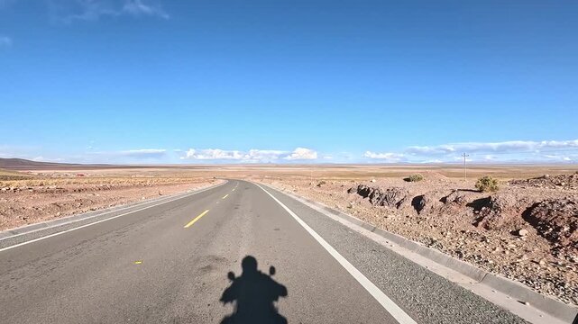 Motorcycle riding from San Pedro de Atacama to Uyuni salt flats. First-person view of high altitude desert road and Altiplano landscape.