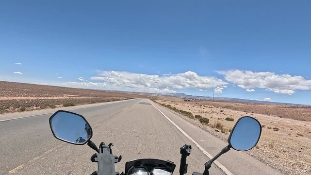 Motorcycle riding from San Pedro de Atacama to Uyuni salt flats. First-person view of high altitude desert road and Altiplano landscape.
