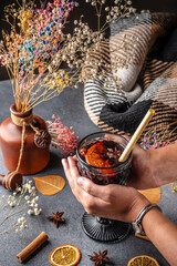 Hands holding hot mulled wine with orange