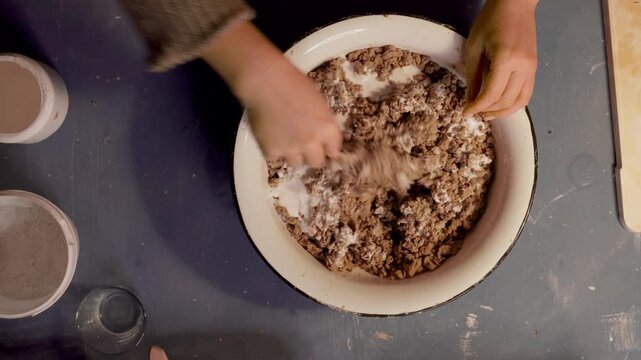 Step 4 of papier mache making process. Hands adding glue to prepared recycled paper pulp to create craft mixture for handmade papier mache projects