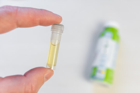 A dose of lactobacilli in a test tube for producing fermented milk products at home, in the background lies a bottle of yogurt, out of focus.