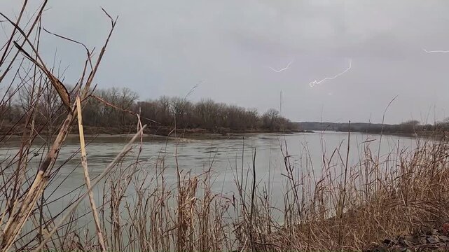 Branching lightning sequence with multiple flashes over river during daytime thunderstorm