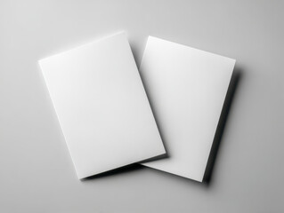 Fototapeta premium Two blank white sheets of paper placed on a smooth gray surface showcasing a minimalist and clean composition ideal for design mockups or presentations