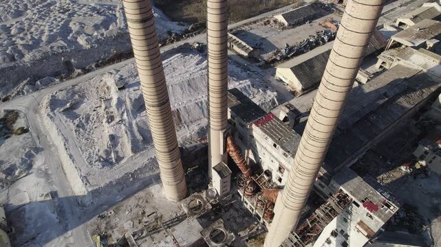Chimneys of an old abandoned factory with an elevator moving camera from the air at a small angle downwards.