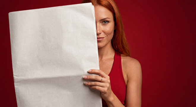 Beautiful redheaded woman in a setting reading a newspaper