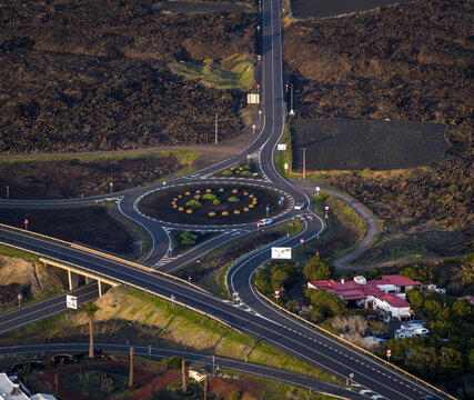 Aerial view of a complex road junction and roundabout cutting through the volcanic landscape, contrasting with the green vegetation, Lanzarote, Canarias, Spain.