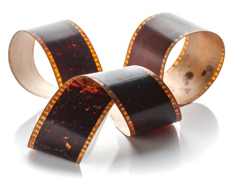 Curled, aged film strip on a reflective surface, highlighting celluloid and sprocket holes
