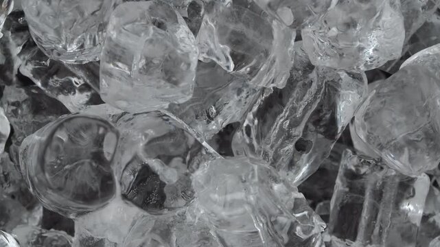 Transparent ice cubes stacked closely in glass against dark background with reflective frozen surface detail visible
