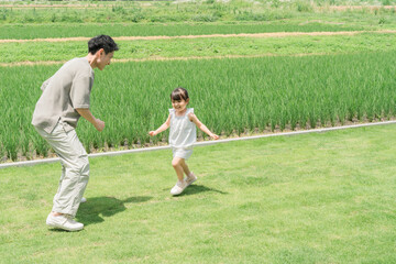 Fototapeta premium A father and daughter playing tag in the lawn of their home.