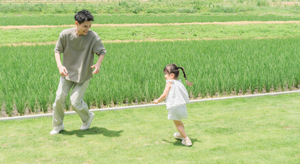 Fototapeta premium A father and daughter playing tag in the lawn of their home.