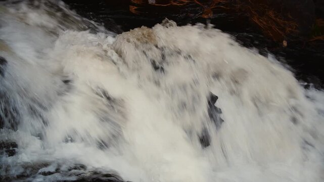 Close up of rushing river water flowing over rocks with motion blur, powerful stream in forest, natural whitewater rapids background