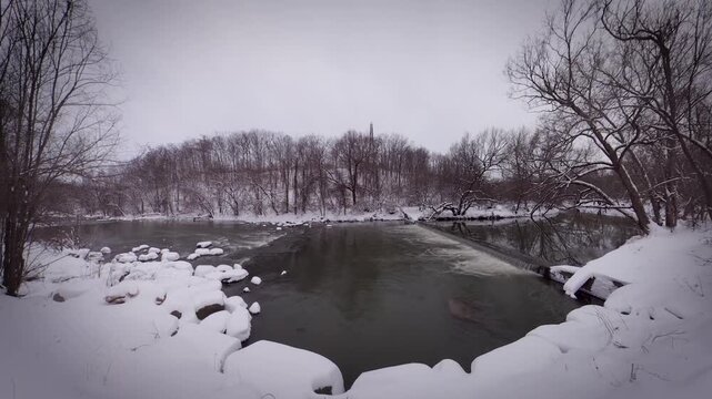 Winter Snow Landscape of Don River Flowing Through Forest in Toronto Canada, Frozen Riverbank and Bare Trees During Overcast Cold Day