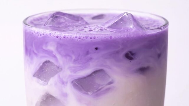 4K Close up side view of trendy iced ube latte with ice cubes, vibrant purple wellness drink. Trendy and aesthetic coffee shop beverage made from purple yam, associated with superfood trends