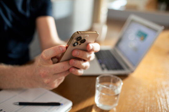 Man using smartphone while working at home laptop