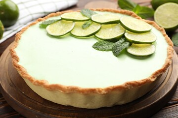 Tasty lime pie with fruit slices and mint leaves on wooden table, closeup © New Africa