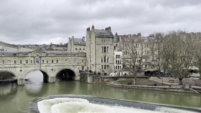 Water flowing over the River Avon weir below Pulteney Bridge in Bath, England.