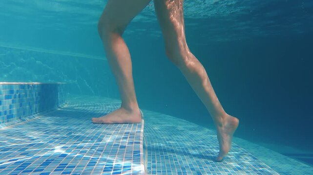 Woman walking underwater on pool stairs in a serene recreational scene